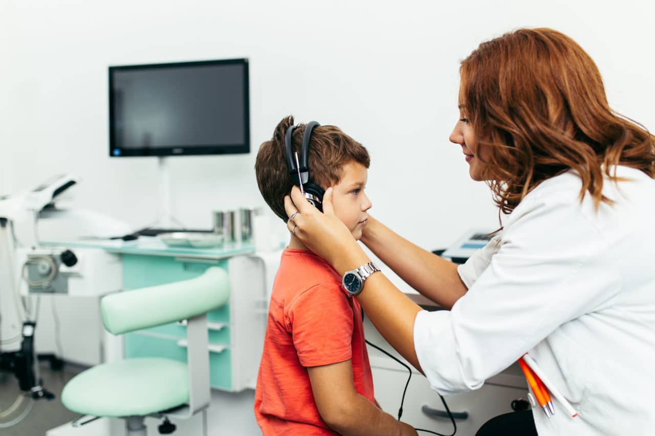Photo of a provider placing headphones on a child in an exam room