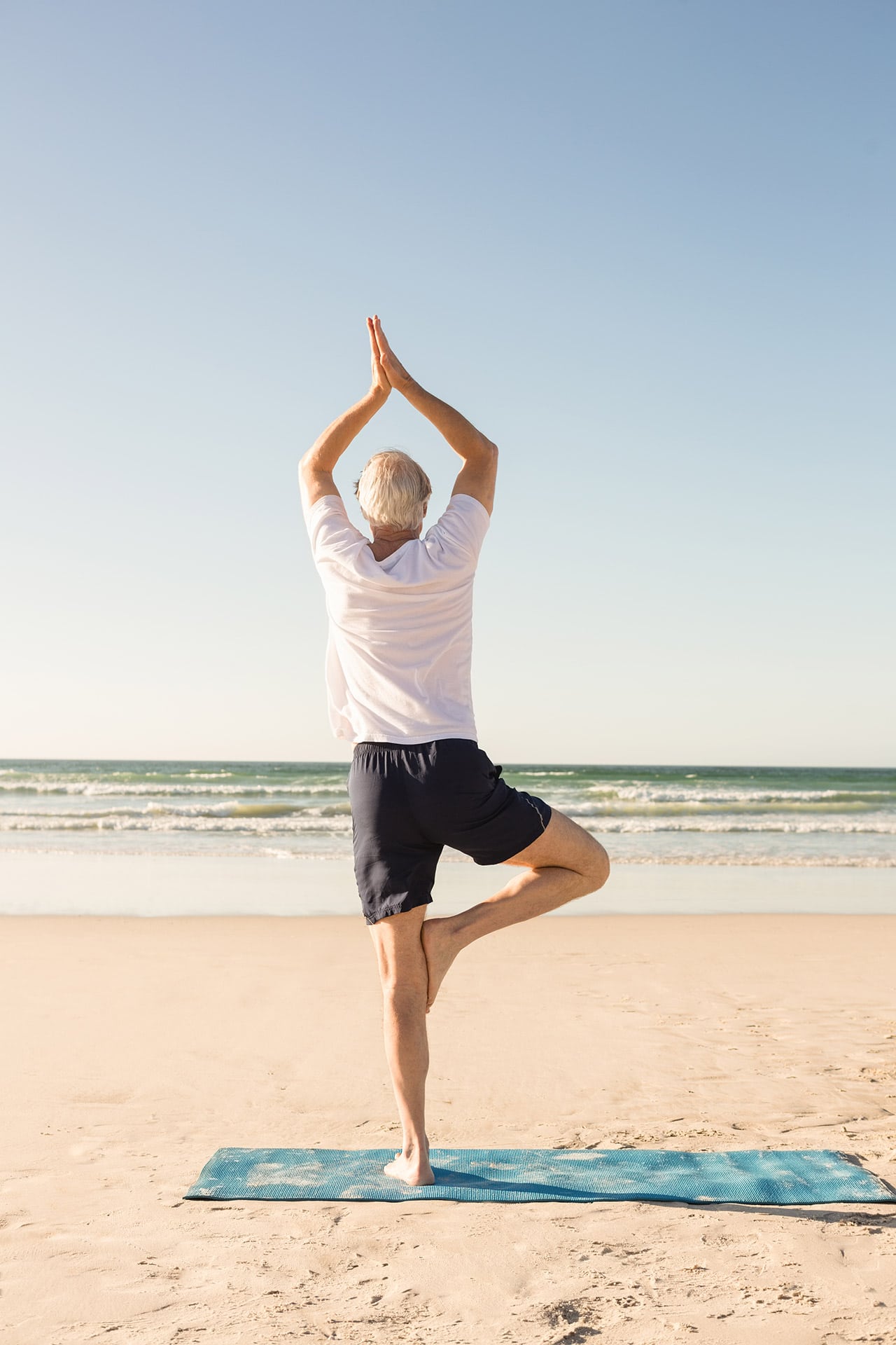 Photo of a person balancing on one leg in a yoga pose on the beach