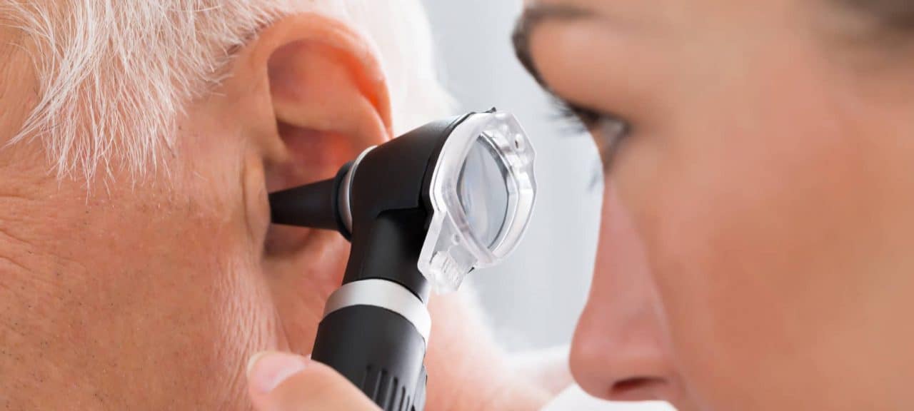 An audiologist examining a patient with an otoscope