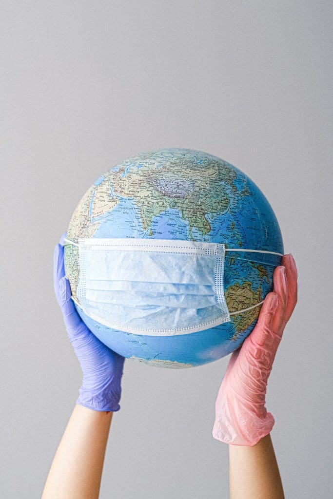 hands holding a globe with a mask 
