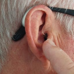 Man points at his hearing aid