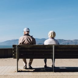 An older couple sitting on a bench together.
