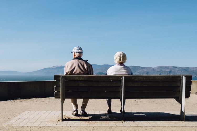 An older couple sitting on a bench together.