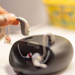 Someone docks their hearing aids on a charger.